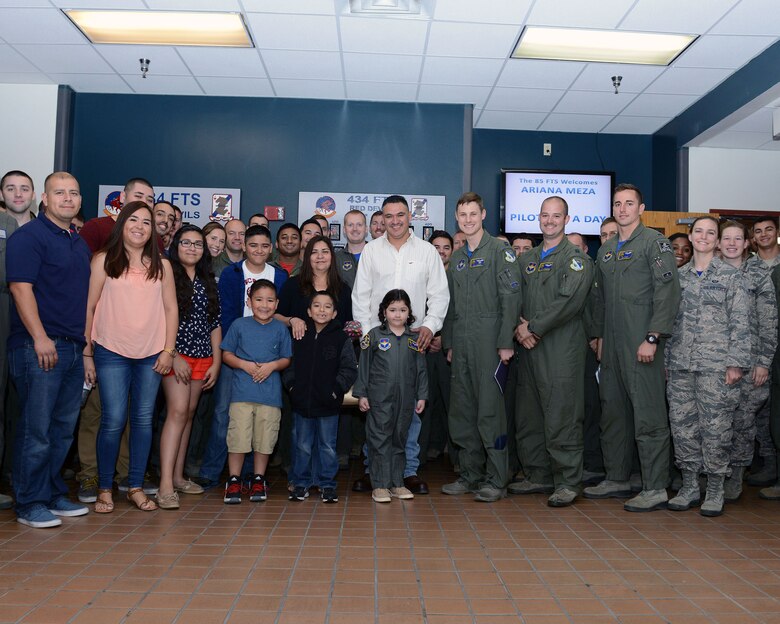 Ariana Meza, center, and her family, pose with pilots from the 47th Operations Group at Laughlin Air Force Base, Texas, March 18, 2016. Meza was selected to be a pilot for a day at Laughlin AFB to learn how pilots operate on a day-to-day basis. (U.S. Air Force photo Senior Airman Jimmie D. Pike) 
