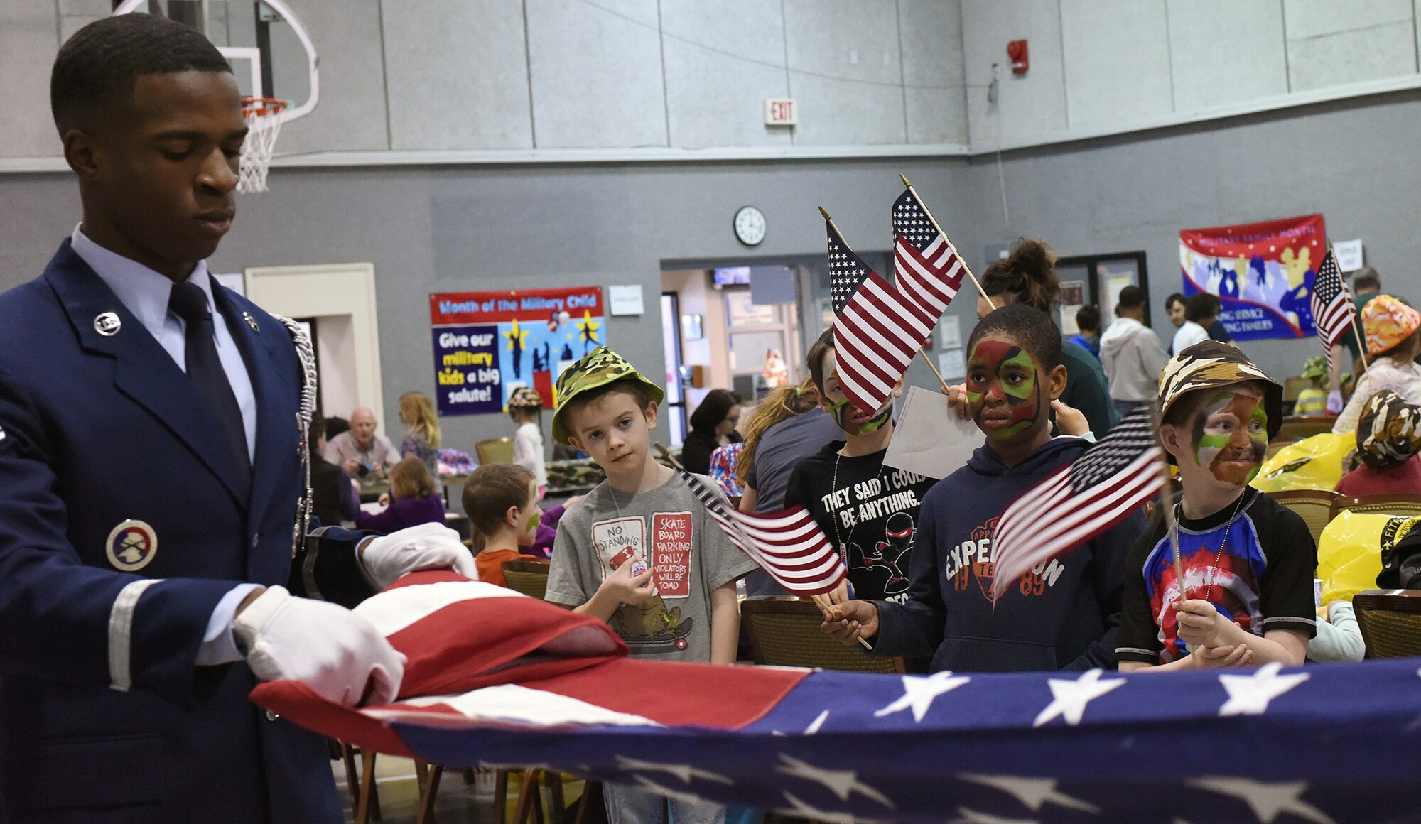 Airman 1st Class Alexander Turner, Malmstrom Honor Guard member, demonstrates a flag folding at the junior deployment line March 23, 2016, at Malmstrom Air Force Base, Mont. The 341st Force Support Squadron hosted the junior deployment to give kids a chance to see what their parents go through before deploying. (U.S. Air Force photo/Senior Airman Jaeda Tookes) 