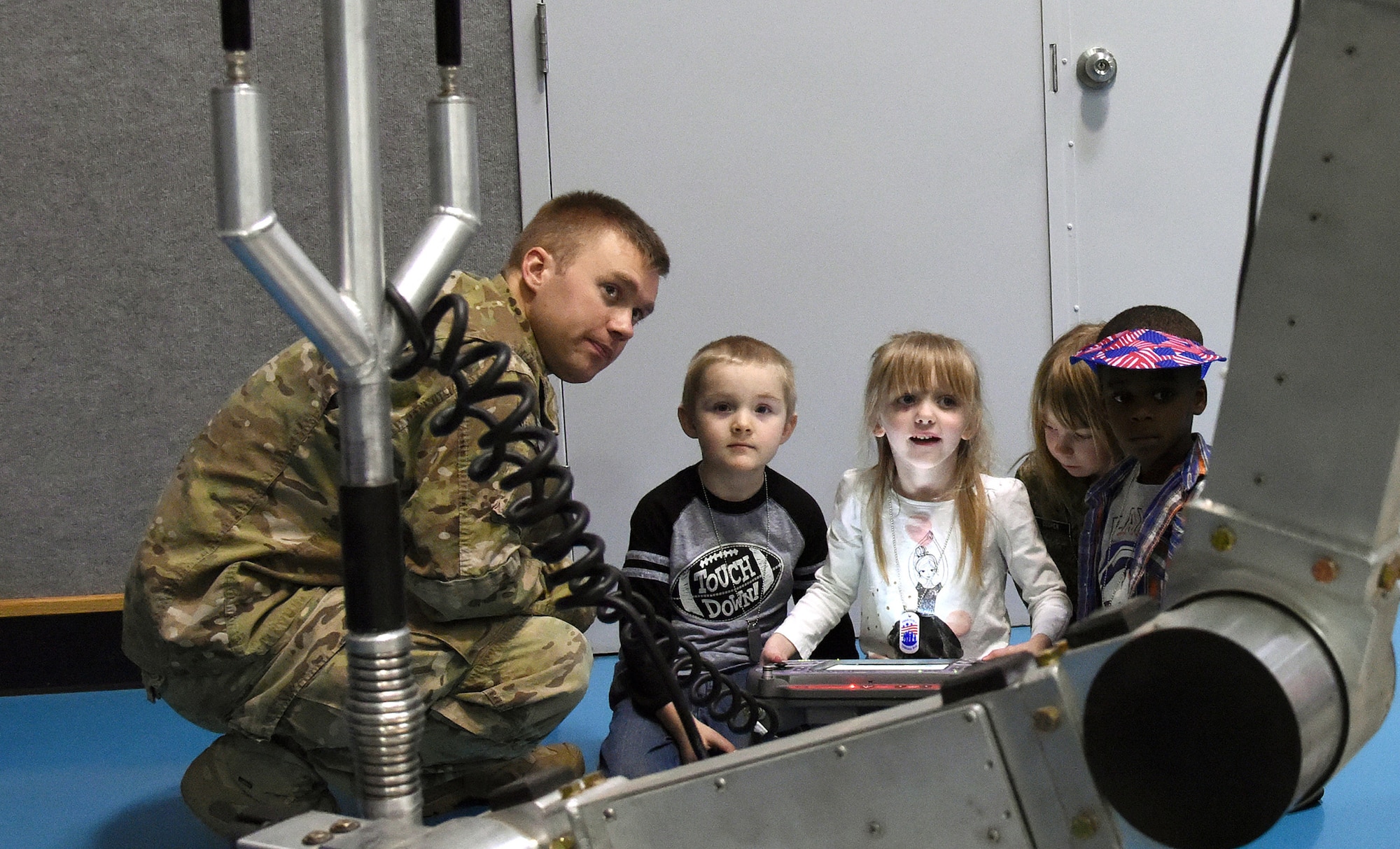Staff Sgt. Michael Muck, 341st Civil Engineer Squadron explosive ordnance team leader, shows children how a medium-size robot works at a junior deployment line March 23, 2016, at Malmstrom Air Force Base, Mont. The 341st Force Support Squadron hosted the junior deployment to give children a chance to see what their parents go through before deploying. (U.S. Air Force photo/Senior Airman Jaeda Tookes) 