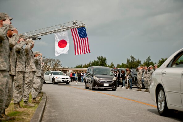 Team Kadena members salute the Japanese and U.S. national flags during Jack Oshiro's memorial procession March 18, 2016, at Kadena Air Base, Japan. The base conducted the memorial procession in memory of Mr. Oshiro who recently passed away. (U.S. Air Force photo by Senior Airman Peter Reft)