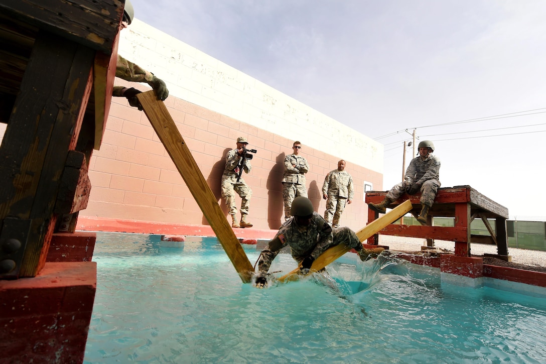 A soldier falls in the water while attempting to cross a leadership reaction course obstacle during Operational Contract Support Joint Exercise 2016 at Fort Bliss, Texas, March 22, 2016. Air Force photo by Staff Sgt. Jonathan Snyder
