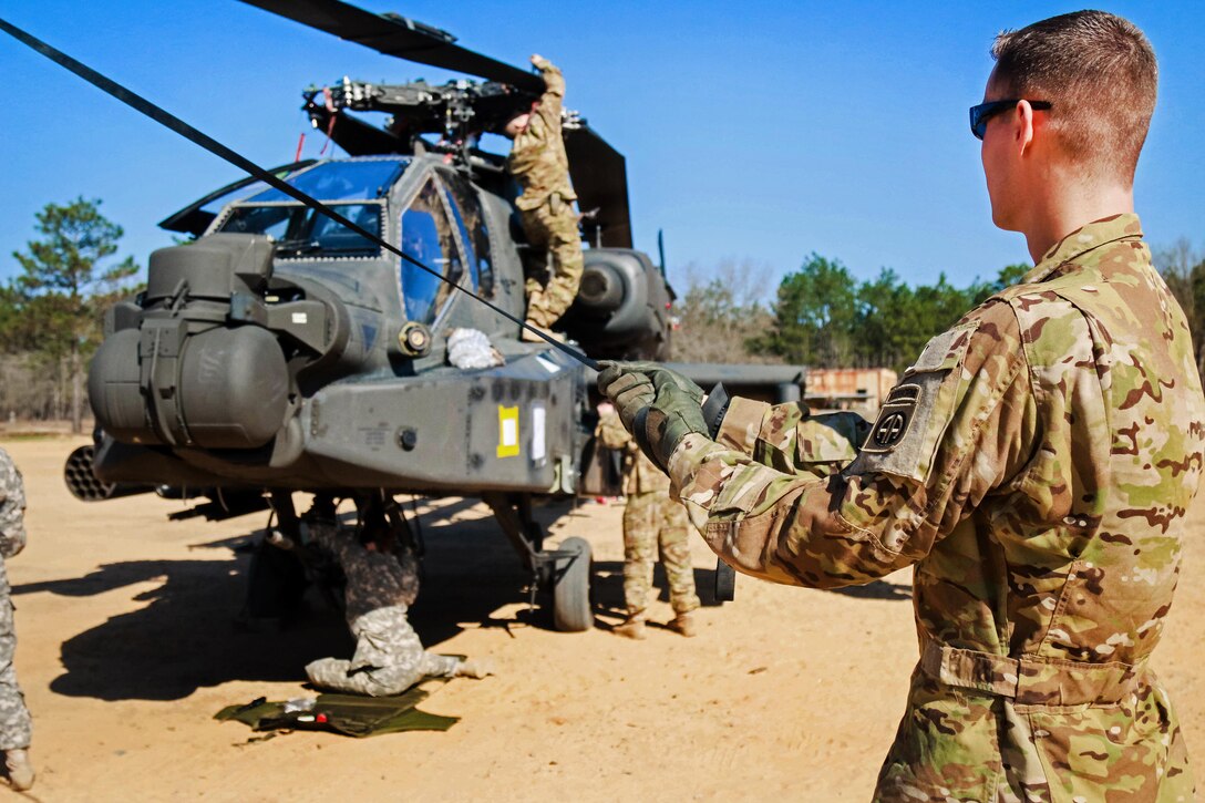A soldier holds a strap while members of a team unfold the rotary blade on an AH-64 Apache helicopter at Camp Mackall, N.C., March 17, 2016. Army photo by Capt. Adan Cazarez