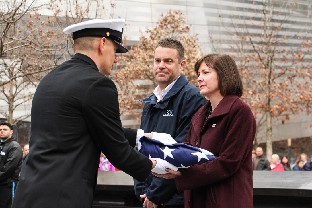 Navy Senior Chief Operations Specialist Ryan King, left, presents a flag flown at Arlington National Cemetery to Heidi Hayden, right, a Marine Corps veteran and chief people officer for the 9/11 Memorial and Museum as Joe Daniels, president of the 9/11 Memorial and Museum, looks on in New York City, March 15, 2016. The flag was presented to the 9/11 Memorial and Museum for its work honoring the historic bond between the Navy and New York City. Navy photo by Lt. Matthew Stroup