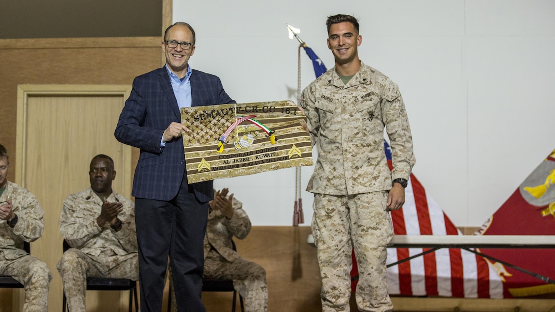 U.S. Marine Cpl. Andrew Gabriel, right, a scout sniper with Charlie Company, 1st Battalion, 7th Marine Regiment, Special Purpose Marine Air Ground Task Force-Crisis Response-Central Command, presents Ambassador Douglas A. Silliman, the U.S. Ambassador to Kuwait, with a gift during the Corporals Course graduation ceremony in Kuwait on March 25, 2016. The corporals’ leadership program is designed to provide instruction for tasks developed in accordance with Marine Corps Order 1510.90, Individual Training Standards. Corporals Course is a professional military education requirement for all corporals to complete in order to be qualified for promotion.