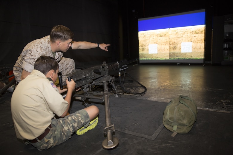Lance Cpl. Christopher Bailey, assaultman, 3rd Battalion, 7th Marine Regiment, directs fire as Devin Castanon, 12, boy scout, Troop 72, prepares to fire a M240B Machine Gun at the Indoor Simulated Marksmanship Trainer during the Boy Scout Camp Out for local Boy Scouts of America troops March 18, 2016.  (Official Marine Corps photo by Sgt. Charles Santamaria/Released)