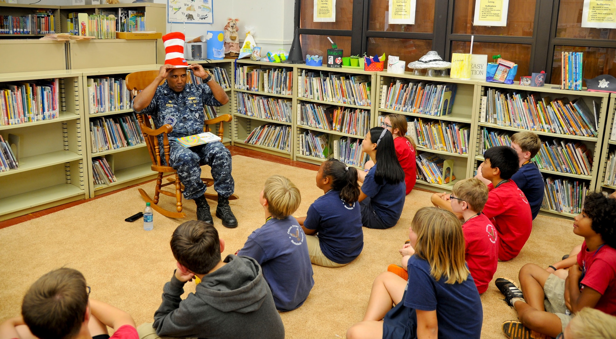 Navy Capt. Stanley Keeves, Joint Base Pearl Harbor-Hickam commander, places a Cat in The Hat-styled top hat on his head before reading to a group of sixth graders at Hickam Elementary School on JBPHH, Hawaii, March 3, 2016. Keeves read to the students as part of the school’s Read Across America event held to celebrate reading and honor renowned children’s book author Dr. Seuss, whose birthday was March 2. (U.S. Air Force photo by Tech. Sgt. Terri Paden) 