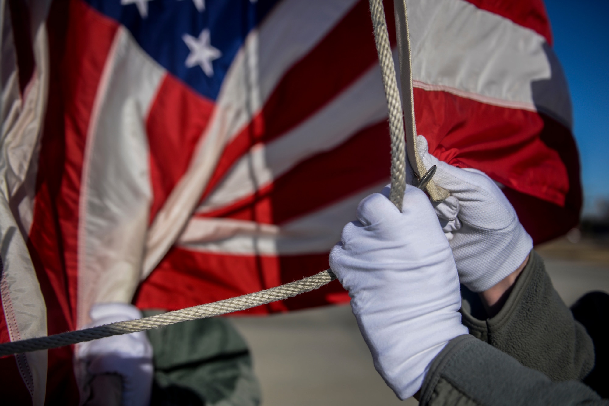 A member of the Honor Guard attaches the ensign to the halyard during practice at Minot Air Force Base, N.D., March 10, 2016. The core mission of the United States Air Force Honor Guard is to provide military funeral honors to veterans and retirees of the Air Force. (U.S. Air Force photo/Airman 1st Class Jessica Weissman)