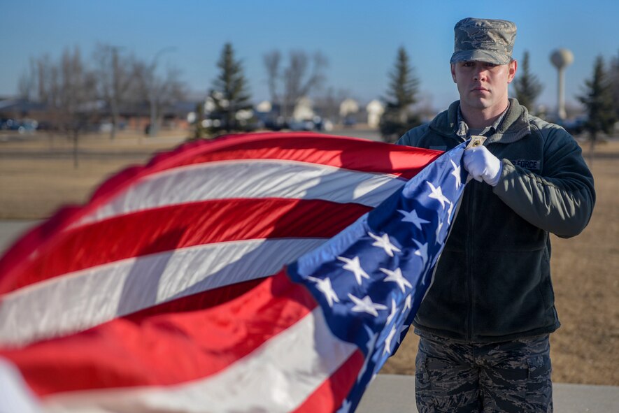 Senior Airman Jonathan Marsh, an airfield system journeyman assigned to the 5th Operations Support Squadron, prepares to fold the flag during a windy practice at Minot Air Force Base, N.D., March 10, 2016. The core mission of the United States Air Force Honor Guard is to provide military funeral honors to veterans and retirees of the Air Force. (U.S. Air Force photo/Airman 1st Class Jessica Weissman)