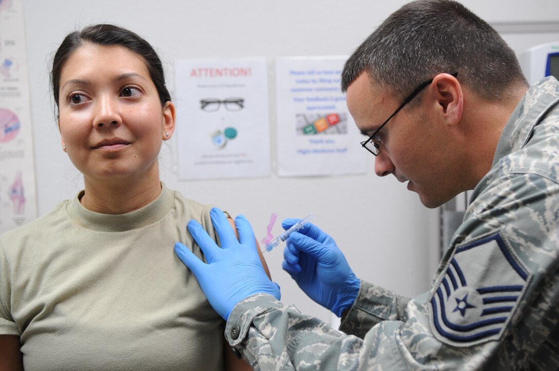 U.S. Air Force Capt. Stephanie Guyette, 489th Bomb Group intelligence officer, left, receives her flu shot from Master Sgt. Wade Melick, 489th Aerospace Medicine Squadron healthcare administrator, March 20, 2016. Guyette is a traditional reservist who spends most of her time as a civilian and then works as an intelligence officer one weekend a month for the 489th Bomb Group. (U.S. Air Force photo by Senior Airman Shannon Hall/Released)