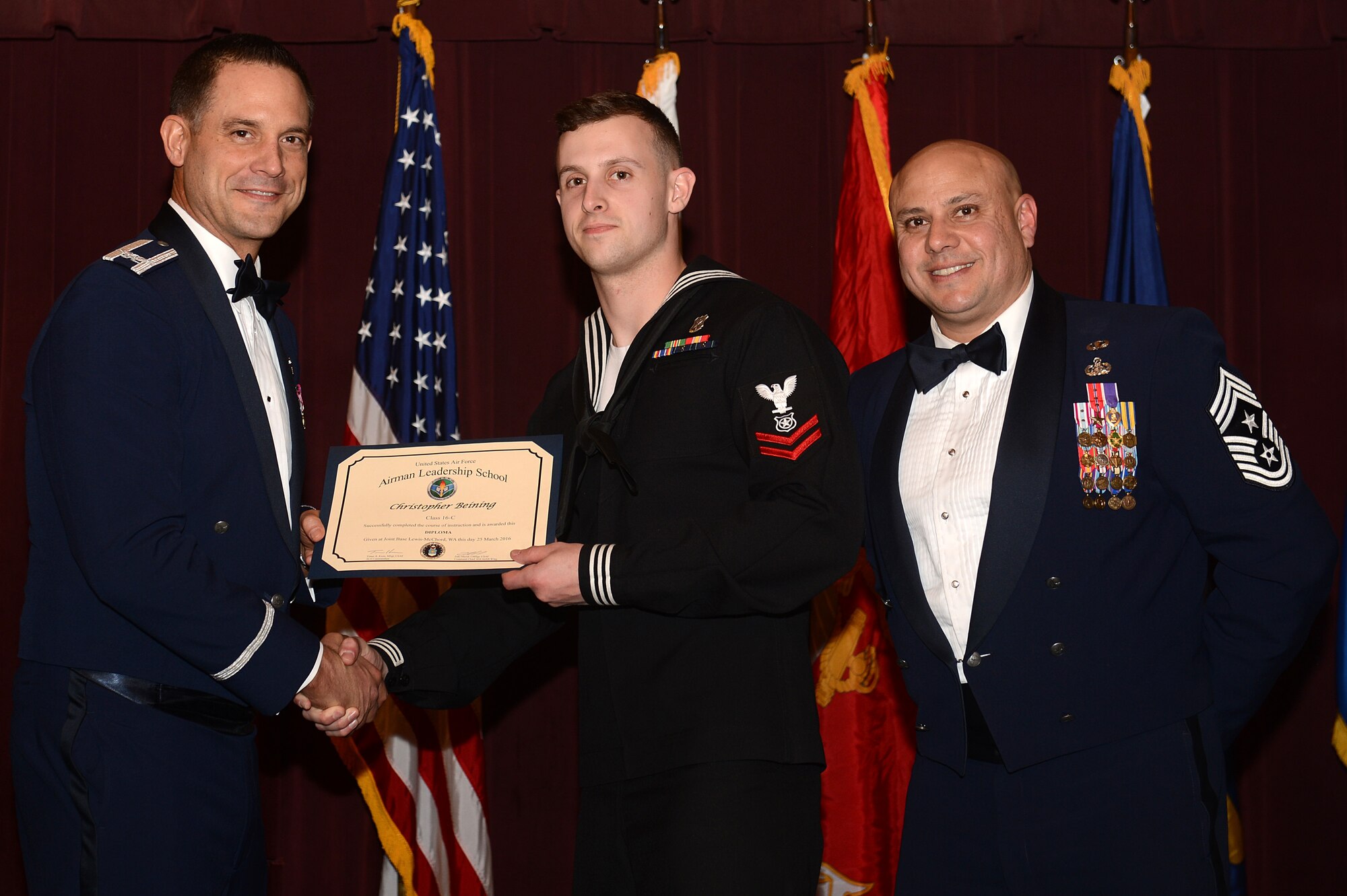 Col. Ethan Griffin (left), 62nd Airlift Wing vice commander and Chief Master Sgt. Tico Mazid, 62nd AW Command Chief present a graduation certificate to MA2 Christopher Beining, Marine Corps Security Forces Battalion master of arms, Naval Base Kitsap during the Julius A. Kolb Airman Leadership School graduation March 25, 2016, at Joint Base Lewis-McChord, Wash. Beining is the first U.S. Navy Sailor to graduate the six-week ALS course here at McChord Field. (U.S. Air Force photo/Senior Airman Divine Cox)