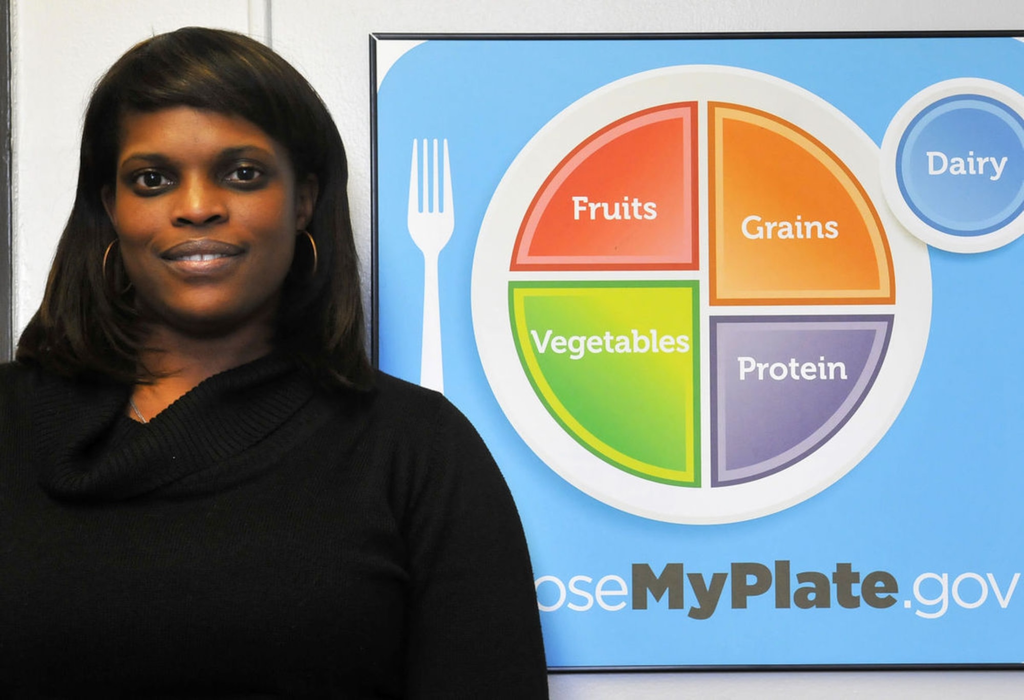 Sonja L. Cooke, JBAB dietitian, poses with the MyPlate Diagram, a guide to help people make well balanced meals. She says managing the quality, frequency and portion control of your meals can help people on their way to living a healthier lifestyle. (U.S. Navy Photo  by Christopher Hurd, Joint Base Journal) 
