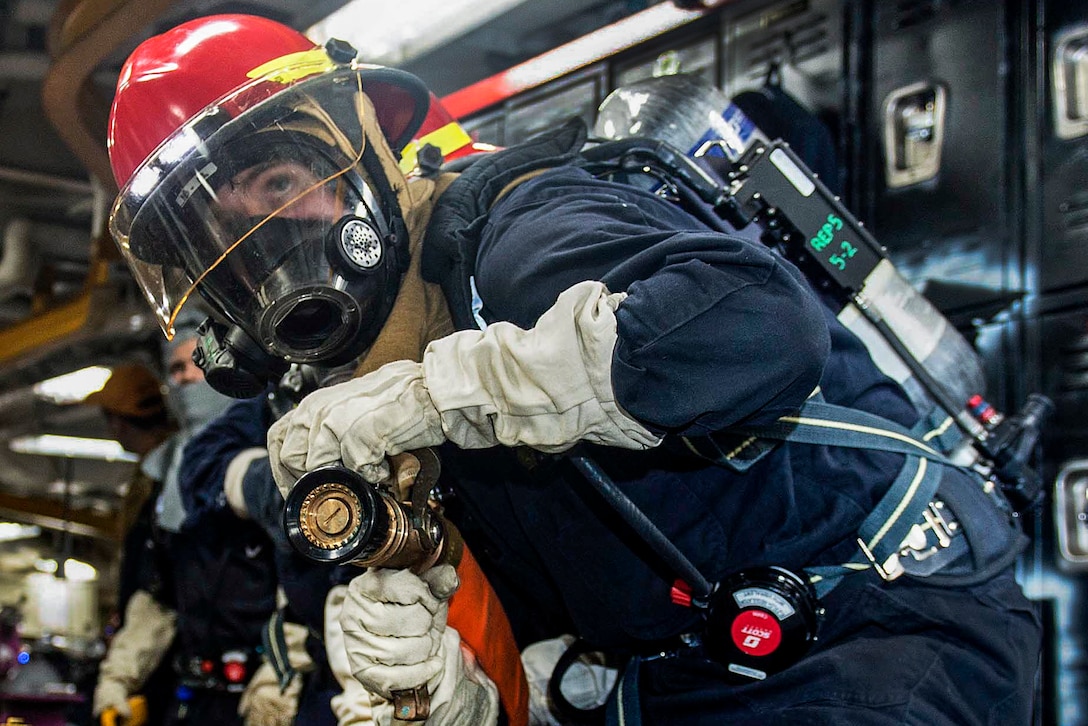 Navy Petty Officer 3rd Class Joseph Parmeley battles a simulated fire during a general quarters drill aboard the aircraft carrier USS Dwight D. Eisenhower in the Atlantic Ocean, March 21, 2016. The aircraft carrier is conducting a Composite Training Unit Exercise to prepare for a future deployment. Parmeley is a machinist's mate. Navy photo by Seaman Casey J. Hopkins