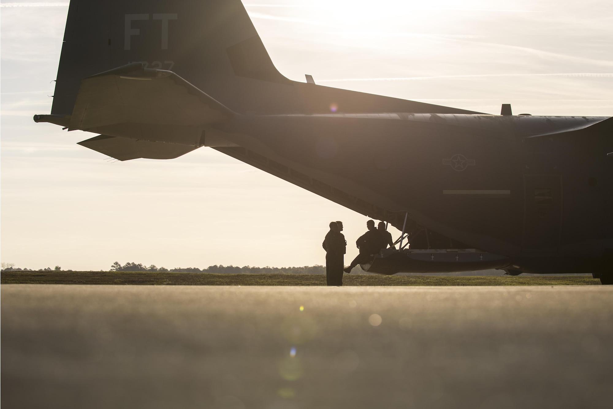 U.S. Air Force Airmen discuss remaining pre-flight procedures under the tail of an HC-130J Combat King II, March 24, 2016, at Moody Air Force Base, Ga. The HC-130J is currently the only dedicated fixed-wing personnel recovery platform in the Air Force inventory.(U.S. Air Force photo by Airman Daniel Snider/Released)
