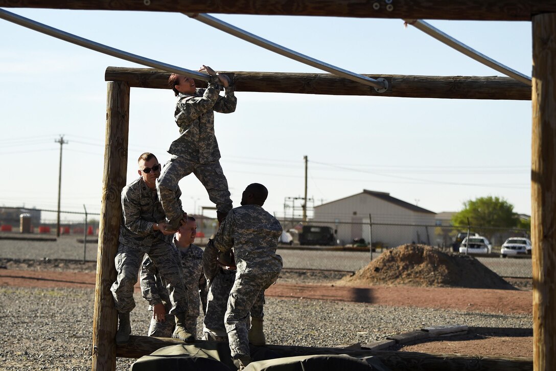 Airmen and soldiers help each other negotiate an obstacle during Operational Contract Support Joint Exercise 2016 at Fort Bliss, Texas, March 22, 2016. Air Force photo by Staff Sgt. Jonathan Snyder