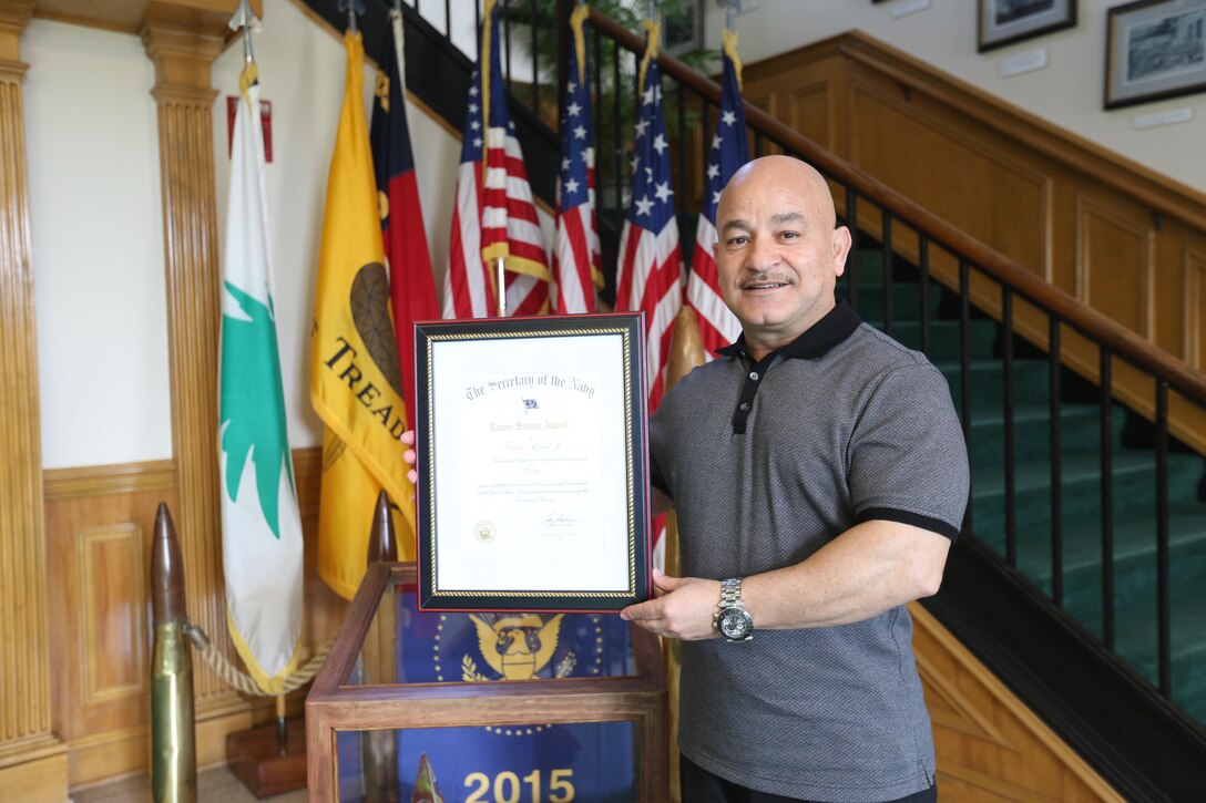 Frank Acevedo Jr., a retired master gunnery sergeant, currently an operations specialist with the Marine Corps Installations East G-3/5 Operations and Planning, proudly displays his recently awarded Career Service Award from the Secretary of the Navy. Acevedo served 32 years in the Marine Corps and has served 11 years of federal service. He was awarded the Career Service Award for his more than 40 years of combined service. (U.S. Marine Corps photo by Cpl. Mark Watola /released)