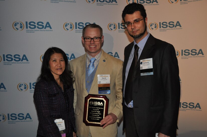 Chief Warrant Officer 3 David Vaughn (middle) accepts the Information Systems Security Association's (ISSA) Annual Volunteer Award from his fellow ISSA members, Andrea Hoy, ISSA President, and Stefano Zanero, ISSA Board of Directors Member, at a ceremony in Raleigh, North Carolina, October 13, 2015. Vaughn is assigned to the U.S. Army Reserve Cyber Operation Group and volunteers a large amount of his free time to civilian and military cyber and information technology based organizations. (Photo: Courtesy of ISSA)