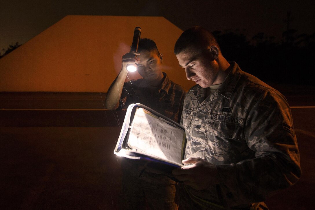 Air Force airman 1st Class Troy Stephenson, right, reads over safety procedures before moving munitions during a no-notice exercise at Kadena Air Base, Japan, March 17, 2016. Stephenson is assigned to the 18th Munitions Squadron. Air Force photo by Senior Airman Omari Bernard
