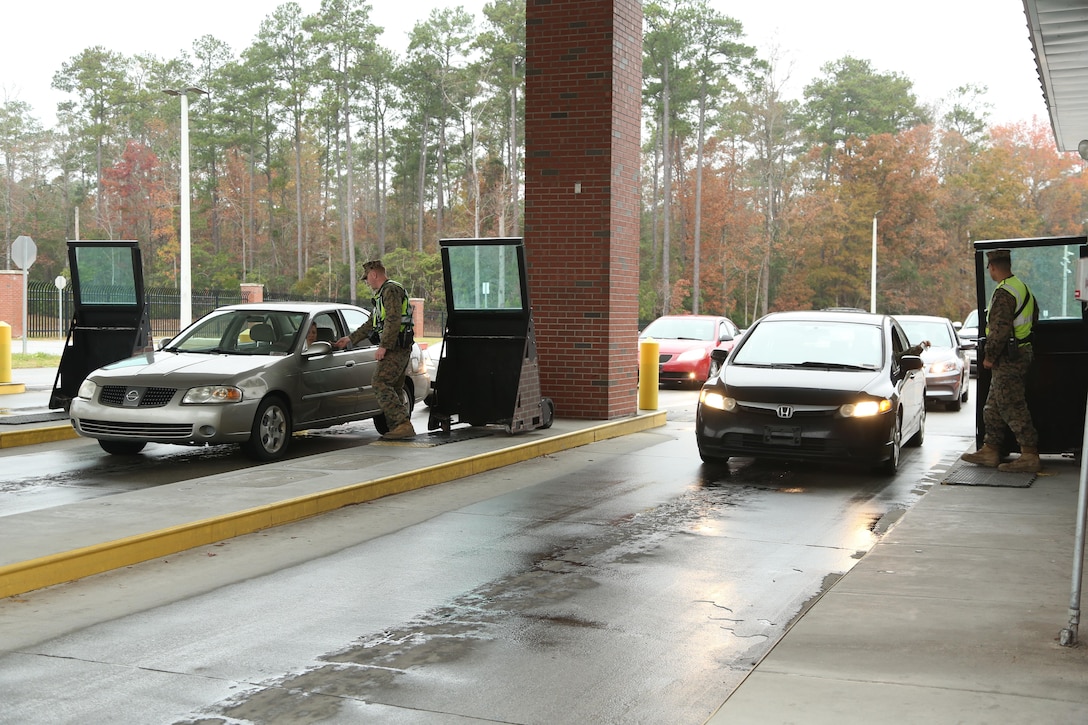 Gate guards with the Provost Marshal’s Office check ID’s of drivers accessing Marine Corps Base Camp Lejeune. Gate guards work around the clock as the first line of defense for the base and its community.  (U.S. Marine Corps photo by Cpl. Mark Watola /released)