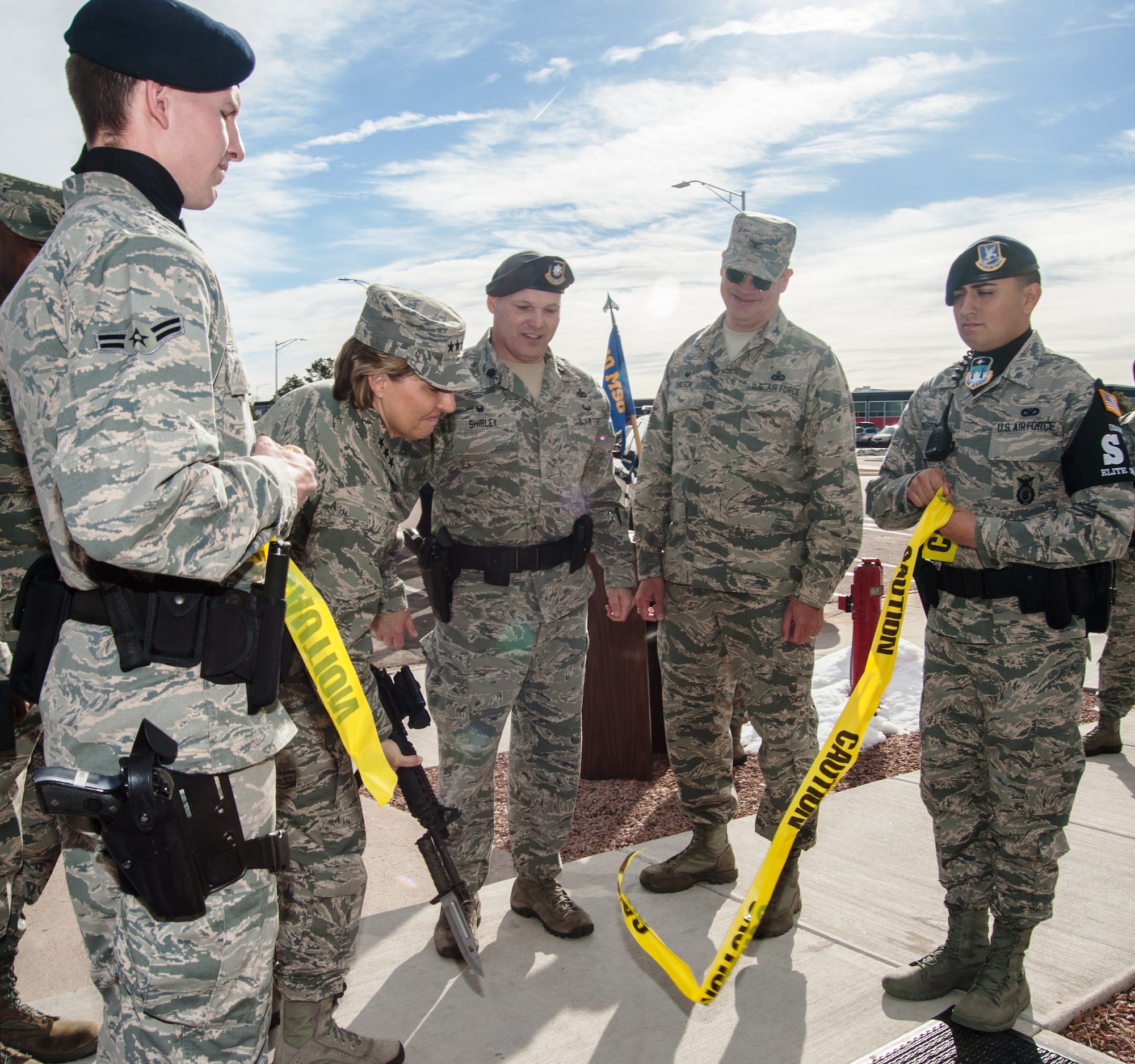 Lt. Gen. Michelle Johnson, the superintendent of the U.S. Air Force Academy, uses an M4 Carbine Rifle to cut the police tape used in place of a ribbon to symbolize the opening of the 10th Security Forces Squadron's newly-renovated building, March 28, 2016. The building was refurbished with equipment and technology upgrades to provide better law enforcement and security services to the Academy community. Lt. Col. Michael Shirley (third from left), commander of the 10th SFS, looks on. (U.S. Air Force photo/Liz Copan)  