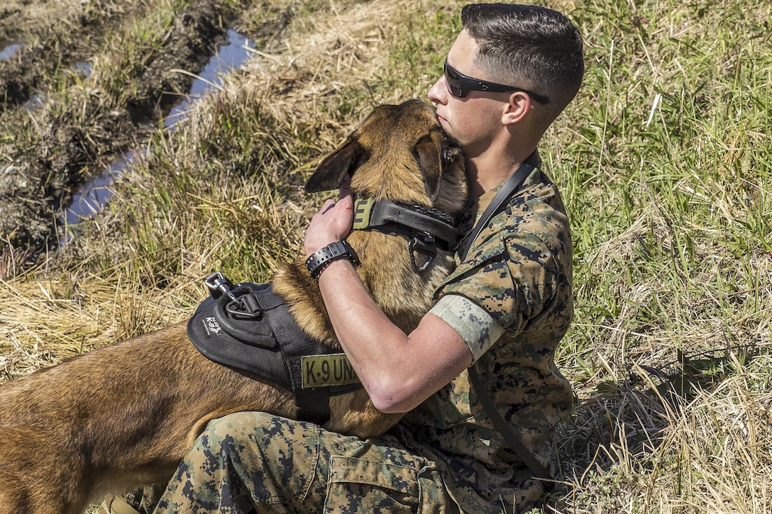 Marine Corps Lance Cpl. Landon Gilliam embraces his K-9 during joint training at Marine Corps Air Station Iwakuni, Japan, March 22, 2016. U.S. and Japanese handlers escorted their working dogs to locate explosives hidden throughout the station’s landfill and harbor areas. Gilliam is a Provost Marshal’s Office military working dog handler assigned to Headquarters Squadron. Marine Corps photo by Lance Cpl. Aaron Henson