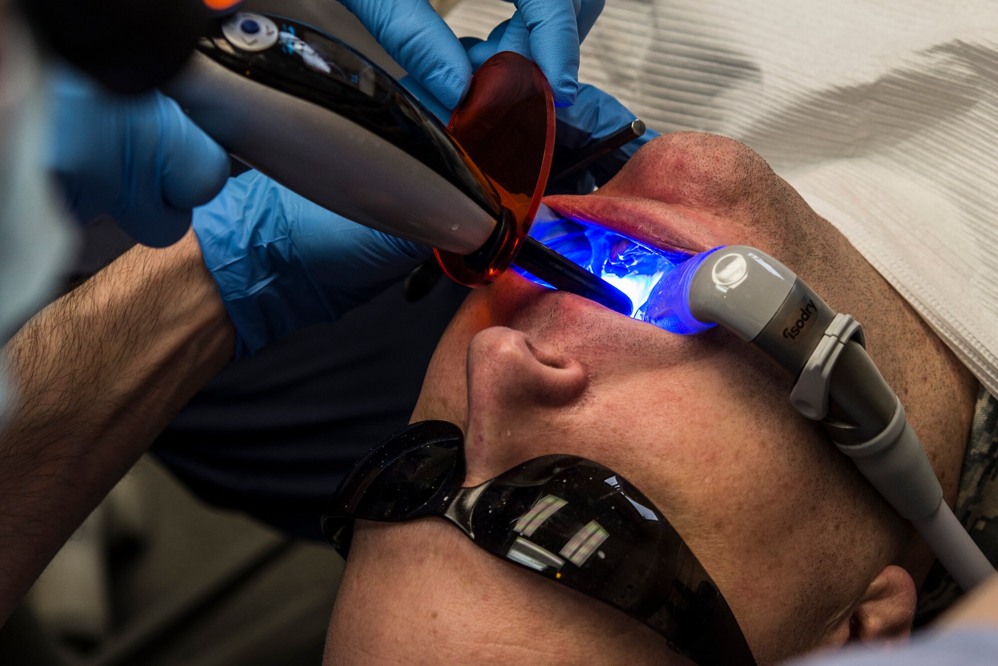 U.S. Air Force Capt. Jeffery Kohler, a 354th Medical Group general dentist, uses a curing light on Master Sgt. Curtis Edwards, of the 354th Maintenance Squadron, March 21, 2016, at Eielson Air Force Base, Alaska. The 354th MDG dental clinic recently received dental equipment that consists of a digital impression machine, a mill and an oven, reduces a three-week, four-appointment process to a same day process completed in a few hours. (U.S. Air Force photo by Staff Sgt. Joshua Turner/Released)