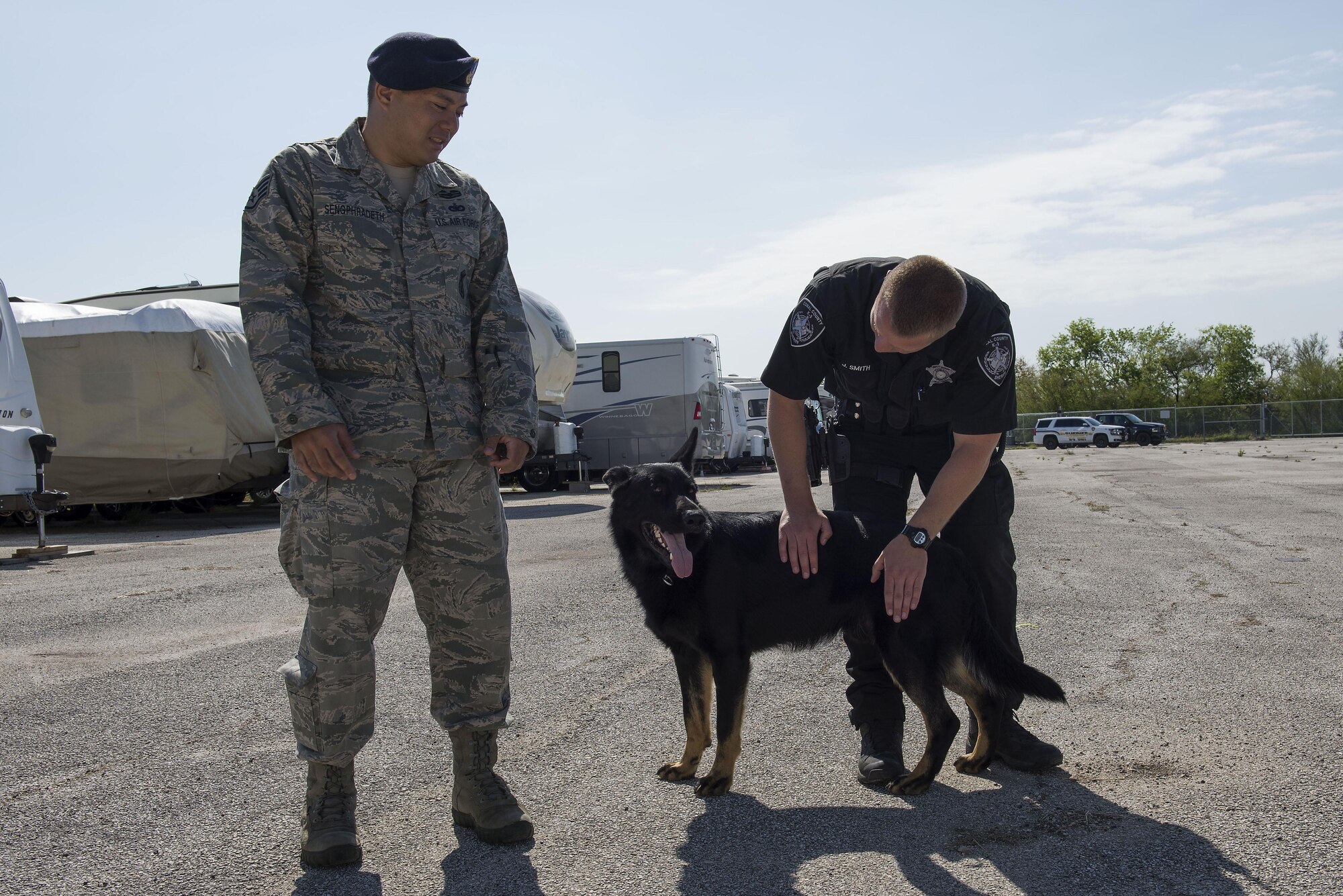 Staff Sgt. Michael Sengphradeth, 902nd Security Forces Squadron military working dog trainer, and Jacob Smith, Comal County Sheriff’s Department K-9 unit dog handler, give positive reinforcement to a police K-9 after completing a training exercise at Joint Base San Antonio-Randolph March 28, 2016. The training exercise was the first in a new partnership between the 902nd SFS and the CCSD K-9 unit. 