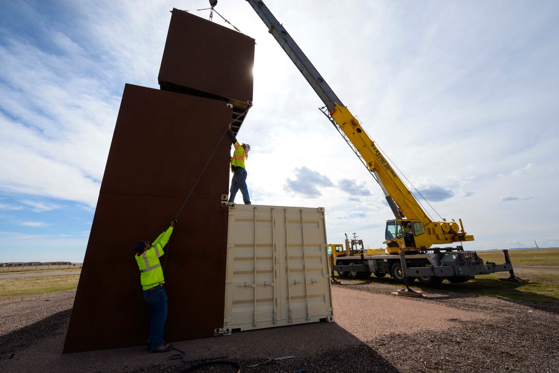 Independent contractors pull on a rope to stack conex buildings during the construction of the Military Operations Urban Terrain training area at Ellsworth Air Force Base, S.D., March 21, 2016. The 28th Security Forces Squadron personnel will use the facility to reinforce team movements to ensure mission success whether in a deployed or home station location. (U.S. Air Force photo by Airman 1st Class Sadie Colbert/Released)