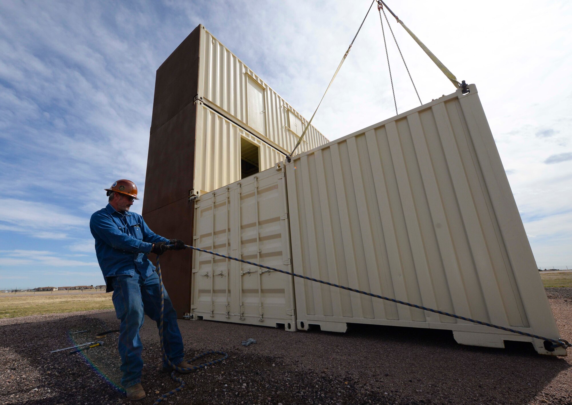 An independent contractor pulls on a rope to place a conex building during the construction of the Military Operations Urban Terrain training area at Ellsworth Air Force Base, S.D., March 21, 2016. The area will be used by the 28th Security Forces Squadron for bi-weekly training to reinforce team movement and cohesiveness among the security flights. The first week of training includes classes to review tactics as well as react to different situations such as flares, incoming in-direct and incoming direct fire, with hands-on training the following week. (U.S. Air Force photo by Airman 1st Class Sadie Colbert/Released)