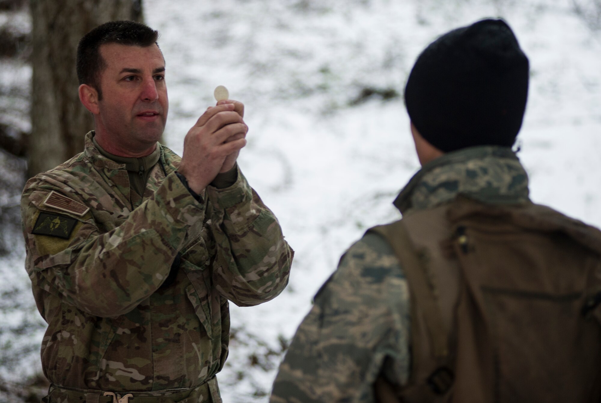 Major Jonathan Harmon, 336th Training Support Squadron combat rescue officer , presents the Eucharist to an Airman in the field March 27, 2016, at Fairchild Air Force Base, Wash. Harmon received special admittance to be able to present the Eucharist himself. (U.S. Air Force photo/Airman 1st Class Sean Campbell)

