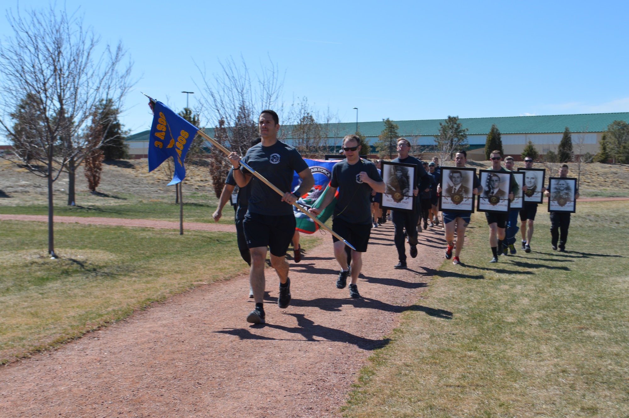 FORT CARSON, Colo. - Airman with the 13th Air Support Operations Squadron hold the images of Tactical Air Control Party Airmen who have lost their lives either deployed or in training during the final mile of the Fifth Annual 24-hour Challenge Run at Fort Carson’s Pershing Field March 24. (Photo by Dani Johnson)