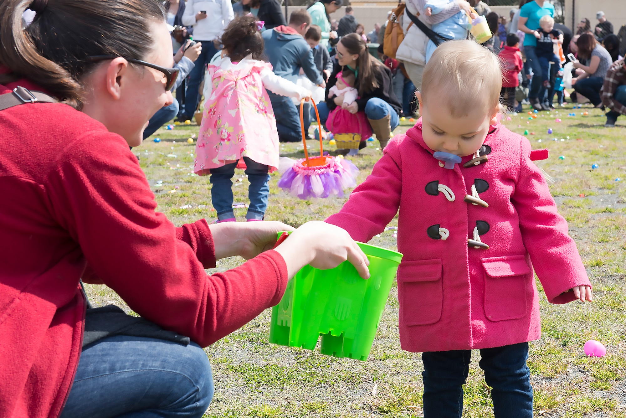 A child places a plastic egg filled with candy into a basket at Yokota Air Base, Japan, March 26, 2016. The eggs contained candy and prize tickets for toys. (U.S. Air Force photo by Senior Airman David C. Danford/Released)