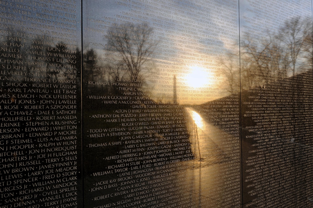 The sunrise and a view of the Washington Monument are reflected in the Vietnam Veterans Memorial in Washington, D.C., March 22, 2016. The memorial comprises two 246-foot-by-9-inch gabbro walls etched with the names of more than 58,000 service members. DoD photo by Marvin Lynchard