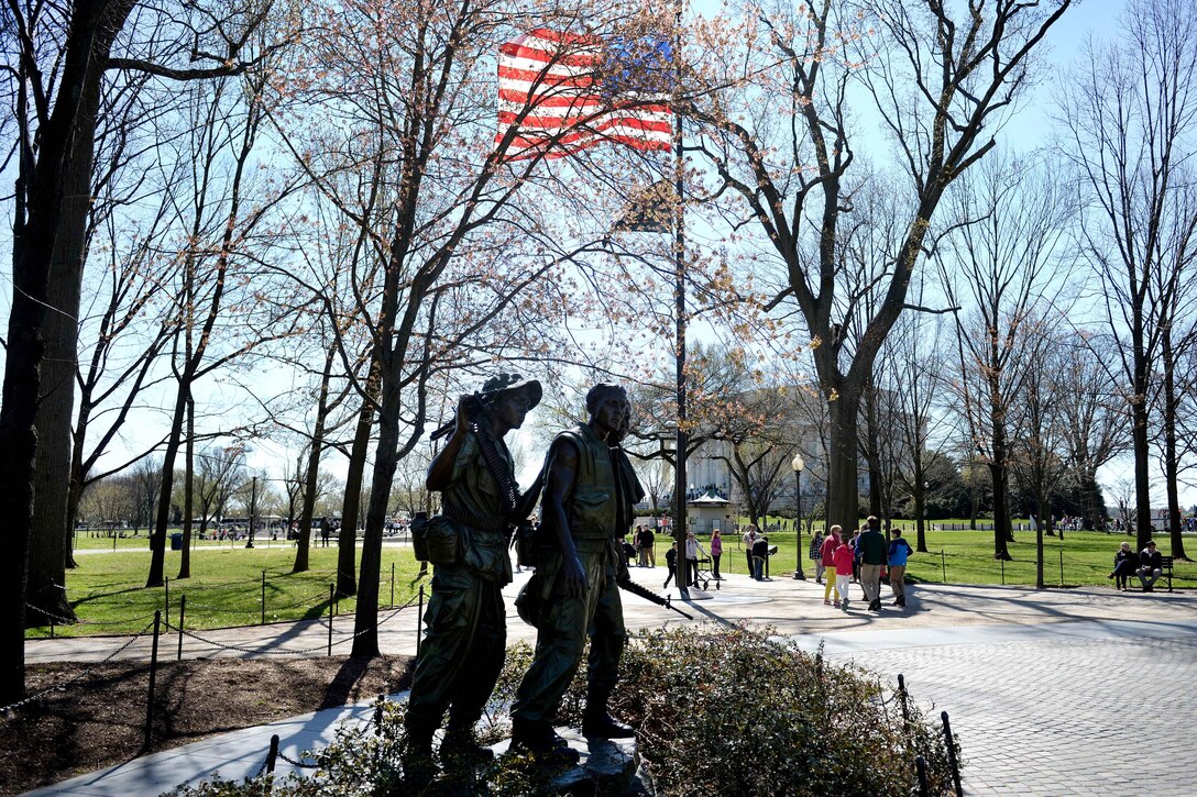 The Three Servicemen or Three Soldiers statue stands near the Vietnam Veterans Memorial, facing the names of their fallen comrades, in Washington, D.C., March 29, 2016. The statue depicts three soldiers -- one Caucasian, one black and one Latino -- to represent the diversity of the U.S. military. DoD photo by Marvin Lynchard