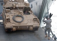 Kuwait Naval Base, Kuwait –A Bradley Fighting Vehicle rolls off the ramp of an Army Logistics Support Vessel during a training exercise.  Army watercraft are designed to operate in austere to bare beach environment and are not dependent upon developed seaports or infrastructure.  1TSC has a vested interest in the operational ability of Army vessels as they are integral to meeting heavy sustainment lift requirements. (US Army photo by Master Sgt. Dave Thompson, 1TSC Public Affairs)