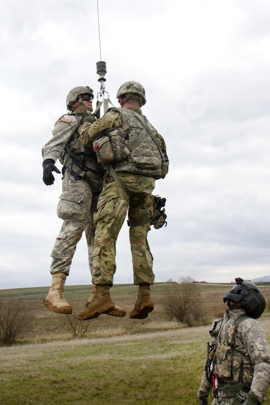 An Army crew chief, right, observes as two soldiers are hoisted up into a UH-60 Black Hawk helicopter during medevac training at Camp Bondsteel, Kosovo, March 15, 2016. Army photo by Staff Sgt. Thomas Duval