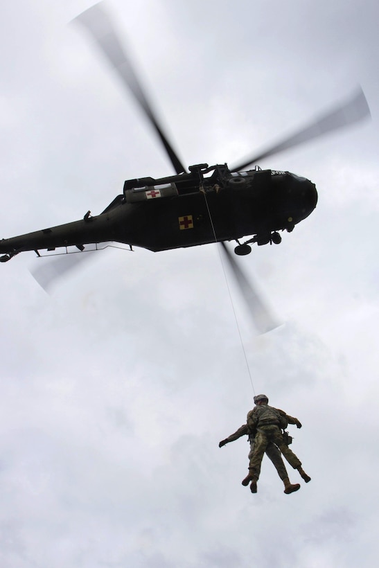 Two soldiers are hoisted up into a UH-60 Black Hawk helicopter during medevac training at Camp Bondsteel, Kosovo, March 15, 2016. Army photo by Staff Sgt. Thomas Duval