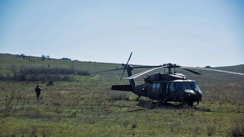 U.S. Marines with Black Sea Rotational Force conduct a patrol with Slovenian soldiers as they pass a Sikorsky UH-60 Black Hawk during Platinum Lynx 16-3 at Babadag Training Area, Romania, March 26, 2016. Marines with BSRF trained with service members from Romania, Bulgaria, and Slovenia in order to develop proficiency in fire and maneuver. 