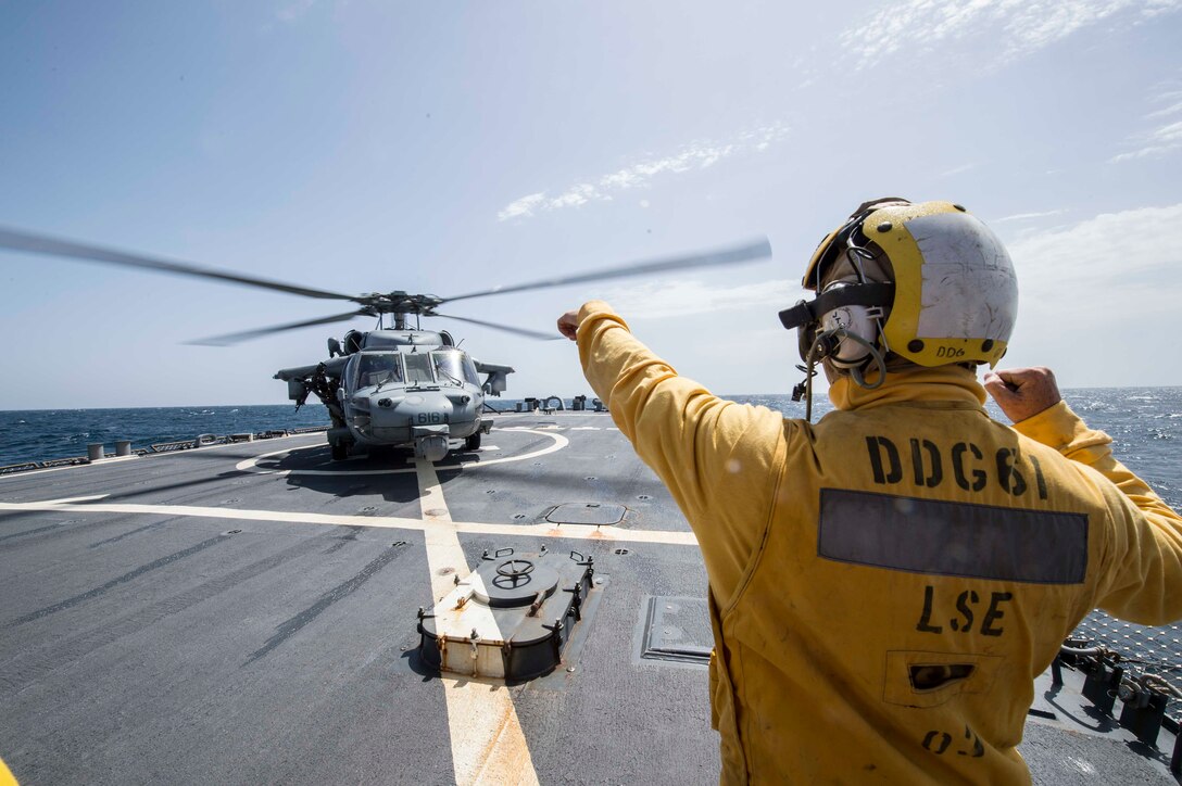 Navy Petty Officer 3rd Class Peter Bowen signals an MH-60 Seahawk helicopter aboard the guided-missile destroyer USS Ramage in the Arabian Gulf, March 19, 2016. The Ramage is supporting Operation Inherent Resolve and other security efforts in the U.S. 5th Fleet area of responsibility. Navy photo by Petty Officer 2nd Class Chase Hawley