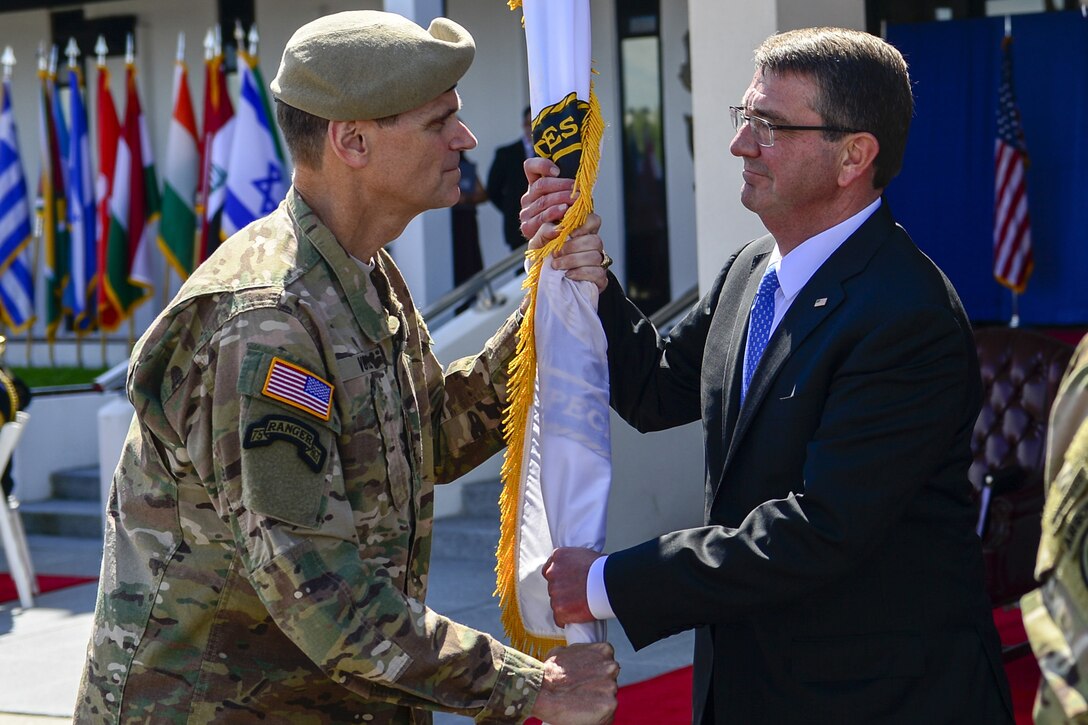 Army Gen. Joseph L. Votel, left, outgoing commander of U.S. Special Operations Command, passes a guidon to Defense Secretary Ash Carter during a change-of-command ceremony at MacDill Air Force Base, Fla., March 30, 2016. Gen. Raymond Thomas assumed command of Socom, while Votel became U.S. Central Command commander in a separate ceremony. Air Force photo by Tech. Sgt. Angelita M. Lawrence