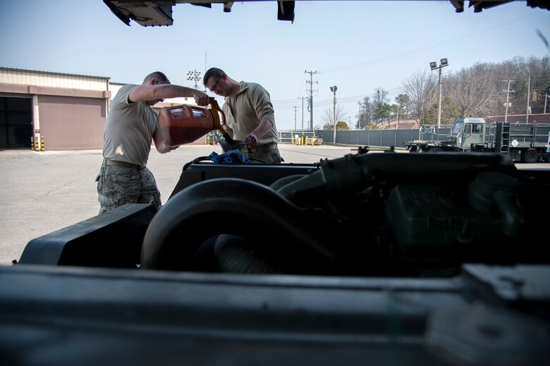 Senior Airman Zachery White and Senior Airman Jonathan Rowley, 51st Logistics Readiness Squadron sorting generating and aircraft sustaining vehicle maintainers, work together to fill a hydraulic fluid reservoir at Osan Air Base, Republic of Korea on March 30, 2016. White and Rowley inspected a Tunner 60K loader to ensure operational order. (U.S. Air Force photo by Staff Sgt. Jonathan Steffen/Released)