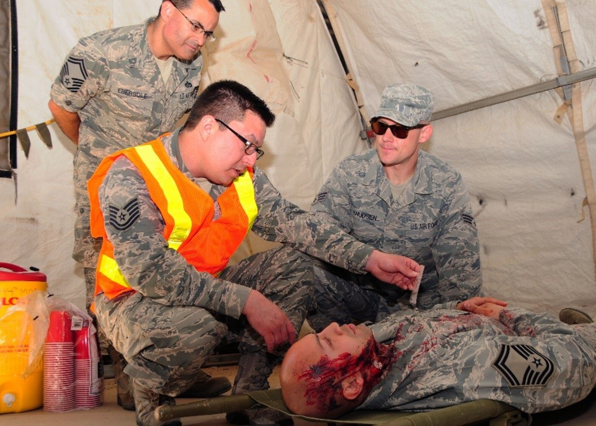 Tech. Sgt.  Thomas Navarro, 944th Medical Squadron medical technician, evaluates a patients symptoms on an exercise card for treatment, processing, and care that Tech Sgt. Ernest Melendez is portraying to have during a training exercise at Luke Air Force Base, Ariz. Senior Master Sgt. Bryan Ebersole and Senior Amn. Karl Knudsen, observe. (U.S. Air Force photo by Tech. Sgt. Louis Vega Jr.)