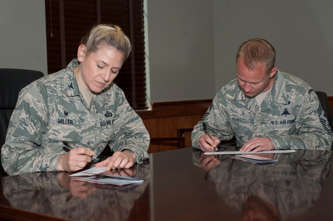 U.S. Air Force Col. Caroline M. Miller, commander of the 633rd Air Base Wing, and Chief Master Sgt. Mark Hurst, command chief of the 633rd ABW, sign Air Force Assistance Fund donation slips at Langley Air Force Base, Va., March 28, 2016. This year’s annual AFAF donation drive kicked off March 21, and seeks to lend critical support to Airmen and their families. (U.S. Air Force photo by Senior Airman R. Alex Durbin)
