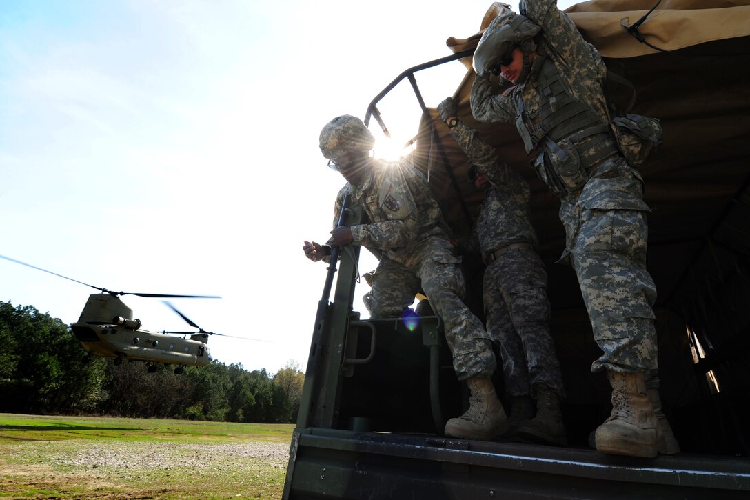 U.S. Soldiers assigned to the 689th Rapid Port Opening Element brace themselves as a CH-47 Chinook passes by during a sling-load training exercise at Fort Eustis, Va., March 24, 2016. The RPOE teamed up with the 7th Transportation Brigade and 11th Aviation Command to practice rigging cargo containers and heavy vehicles as well as familiarizing themselves with casualty evacuations. (U.S. Air Force photo by Staff Sgt. Natasha Stannard) 