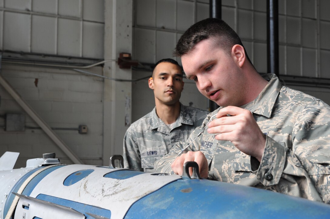 U.S. Air Force Senior Airman Christopher Lewis, a squadron lead crew member assigned to the 1st Maintenance Group, trains Airman 1st Class Christopher Francher, a weapons load crew member assigned to the 94th Aircraft Maintenance Unit, on bomb inspection criteria at Langley Air Force Base, Va., March 23, 2016. Weapons load crew members are entrusted with properly securing munitions to aircraft, therefore requiring consistent training and evaluation. (U.S. Air Force photo by Senior Airman Brittany E. N. Murphy)