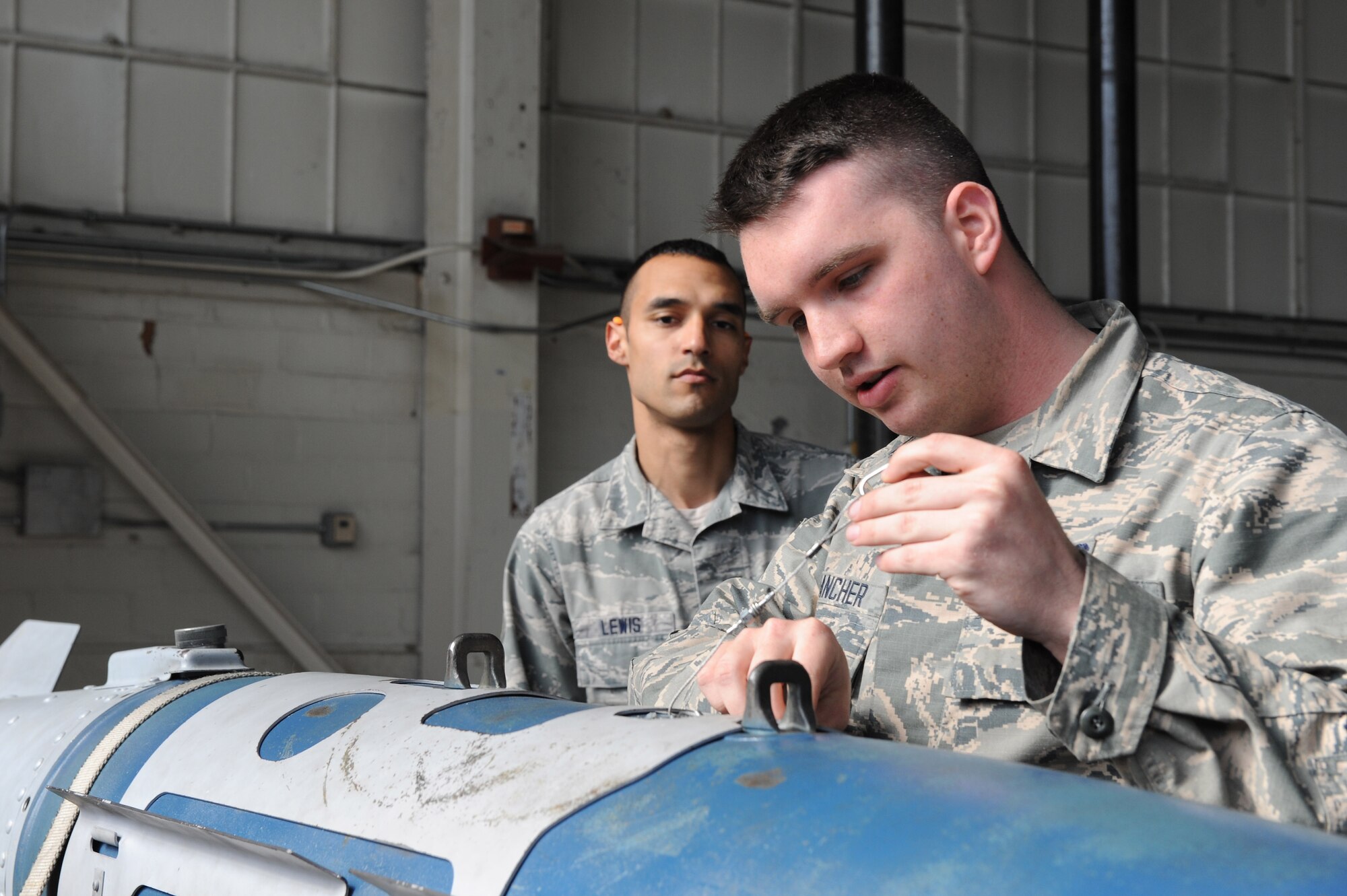 U.S. Air Force Senior Airman Christopher Lewis, a squadron lead crew member assigned to the 1st Maintenance Group, trains Airman 1st Class Christopher Francher, a weapons load crew member assigned to the 94th Aircraft Maintenance Unit, on bomb inspection criteria at Langley Air Force Base, Va., March 23, 2016. Weapons load crew members are entrusted with properly securing munitions to aircraft, therefore requiring consistent training and evaluation. (U.S. Air Force photo by Senior Airman Brittany E. N. Murphy)
