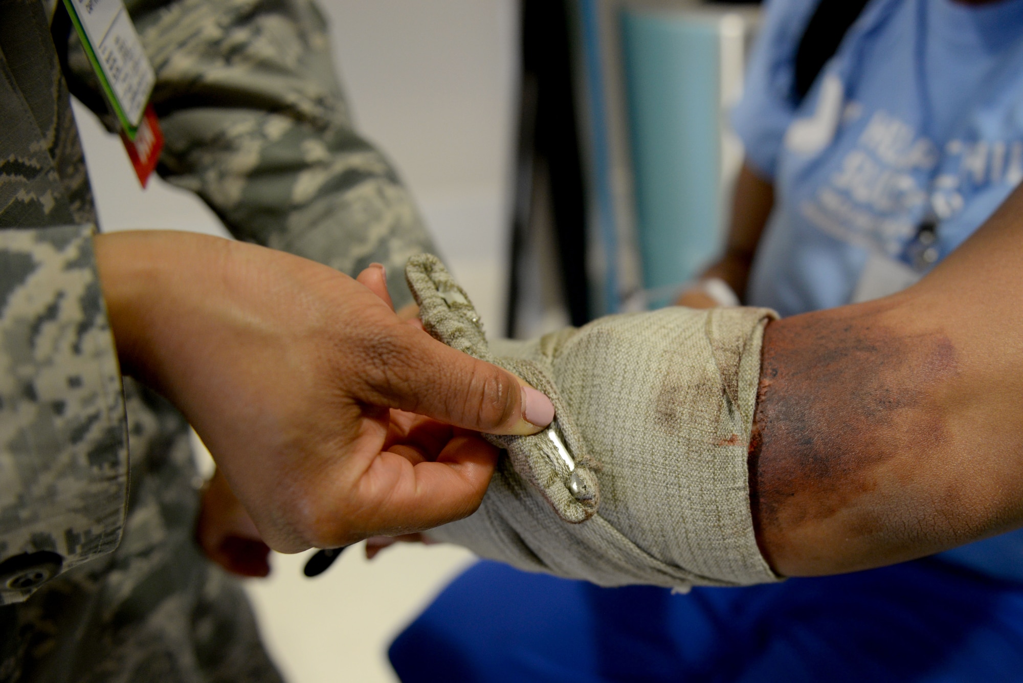A U.S. Airman assigned to the 633rd Medical Group secures a tourniquet on the arm of a simulated injured patient during a mass casualty exercise at Langley Air Force Base, Va., March 24, 2016. The exercise allowed the medical staff to strengthen their capabilities and become familiar with mass casualty situations. (U.S. Air Force photo by Airman 1st Class Kaylee Dubois)