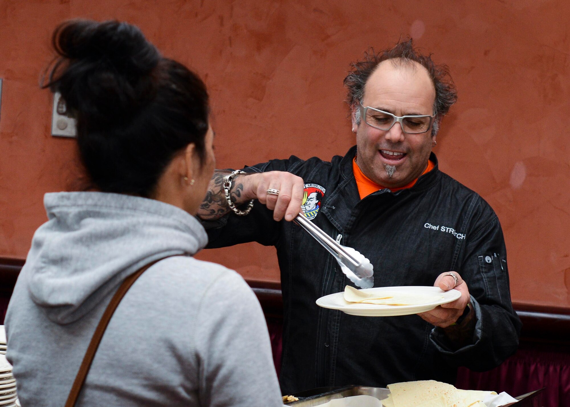 Chef Stretch, one of the “Messlords” members, serves food during a Mexican-themed lunch, March 25, 2016, at Aviano Air Base, Italy. He and the other Messlords travel around the globe preparing meals for Service members. (U.S. Air Force photo by Senior Airman Austin Harvill/Released)