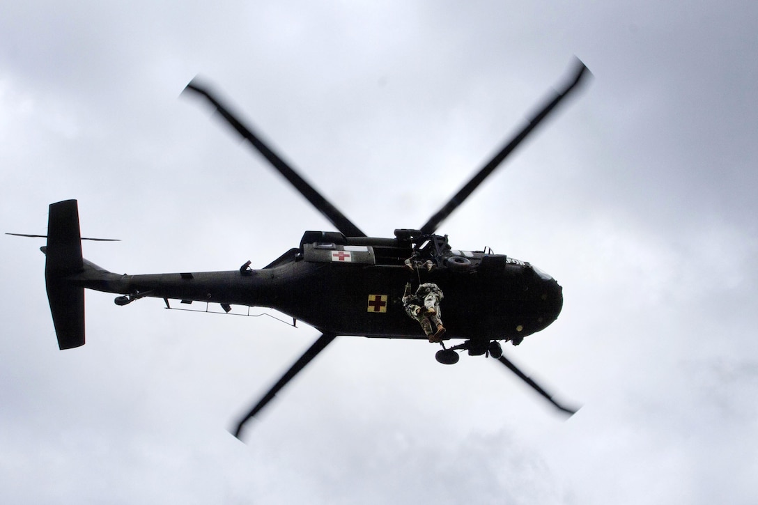 A helicoper crew hoists two soldiers into a UH-60 Black Hawk during medevac training at Camp Bondsteel, Kosovo, March 15, 2016. Army photo by Staff Sgt. Thomas Duval