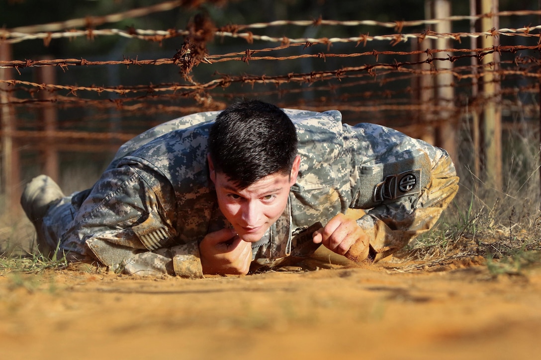 A paratrooper crawls under a barbed wire obstacle during physical fitness training at Fort Bragg, N.C., March 24, 2016. Army photo by Sgt. Anthony Hewitt