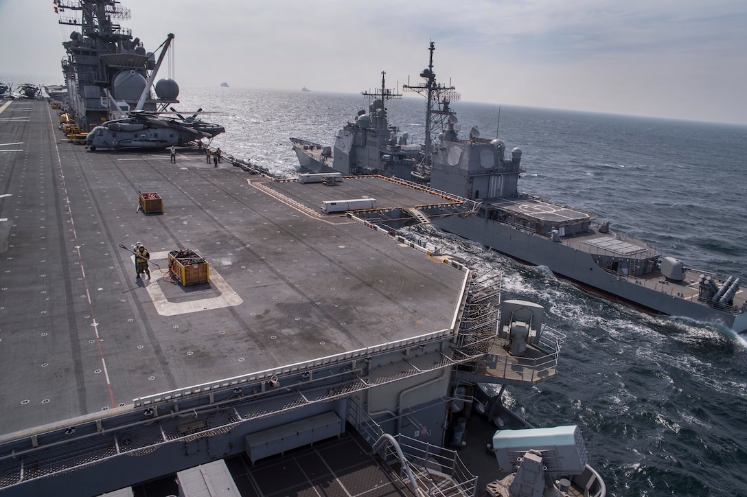 Sailors and Marines conduct vertical replenishment operations on the flight deck aboard the amphibious assault ship USS Bonhomme Richard, left, along with guided-missile cruiser USS Shiloh in the East Sea, March 16, 2016. Navy photo by Petty Officer 3rd Class Jeanette Mullinax